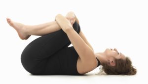 caucasian woman on the floor, in relaxed yoga pose, side view, dressed in black on white background