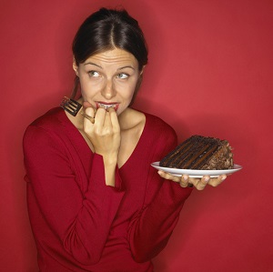 Conflicted woman holding chocolate cake
